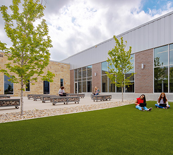 Image of a middle school courtyard with benches and students working in the green space.